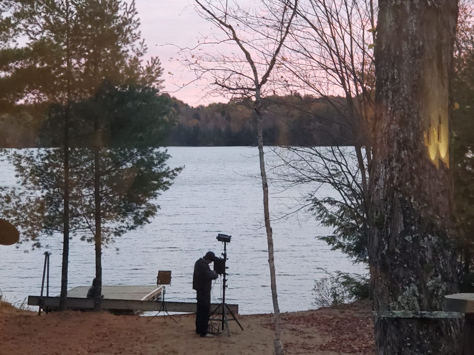 A crew member adjusting a light stand by the dock at dusk