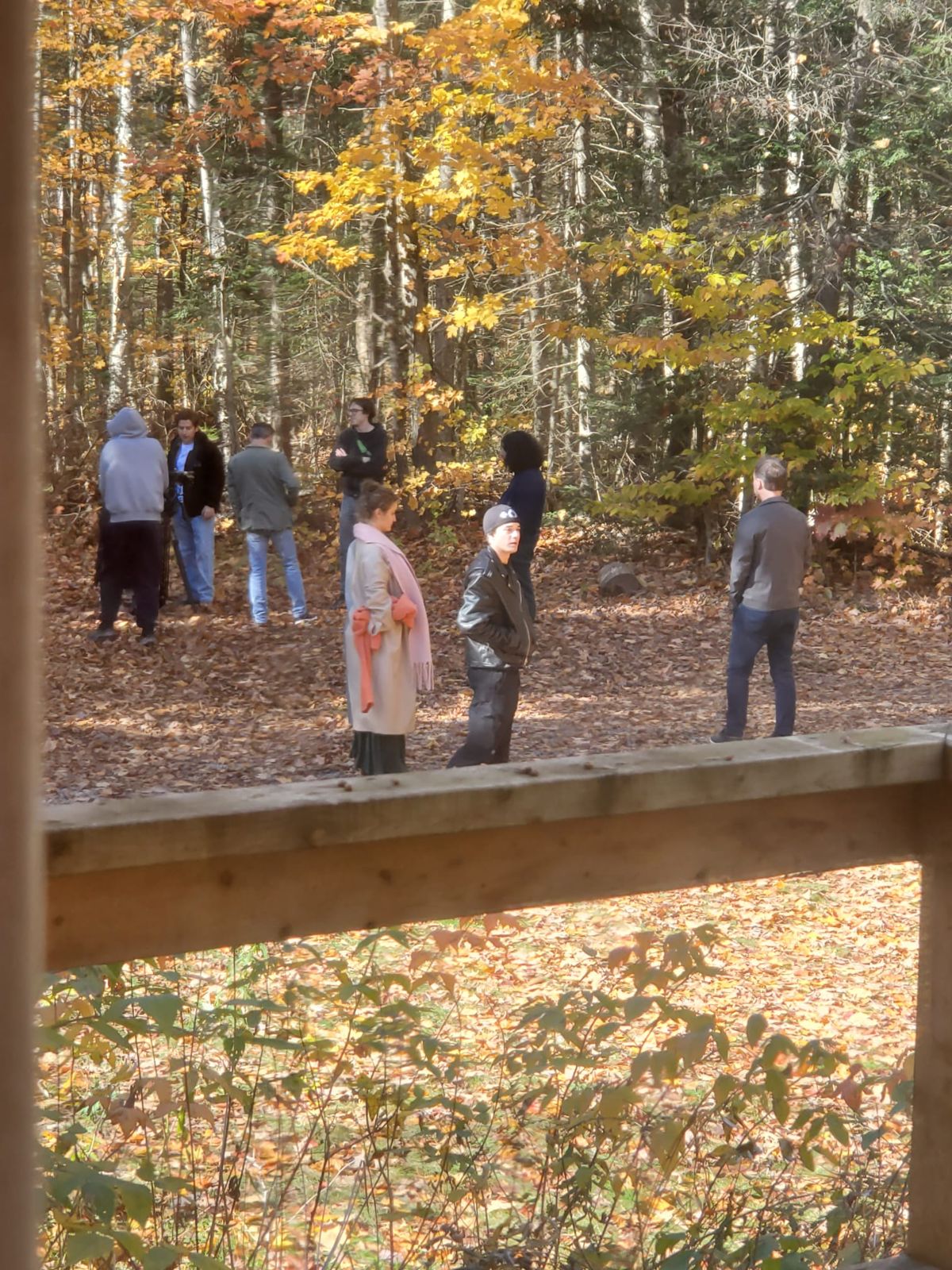 Cast and crew rehearsing in a leaf-covered clearing in the woods