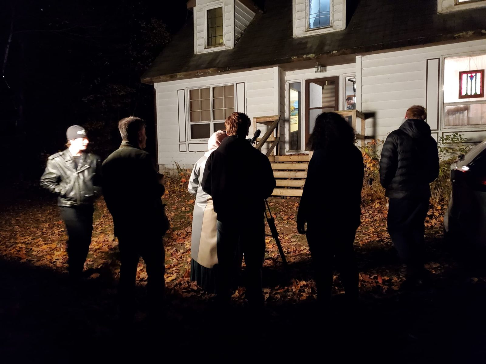 Cast and crew lit in the front yard facing the lakehouse at night