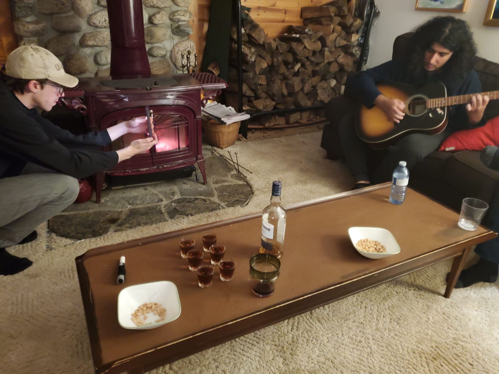 A crew member filming with a phone beside the stove while an actor plays guitar