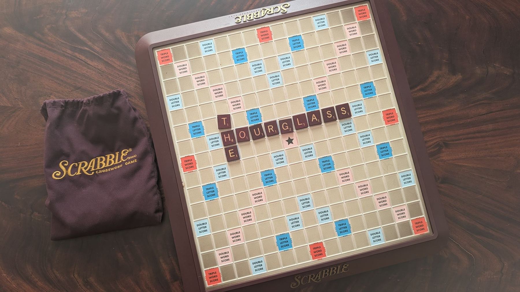 Scrabble tiles spelling THE HOURGLASS on a board