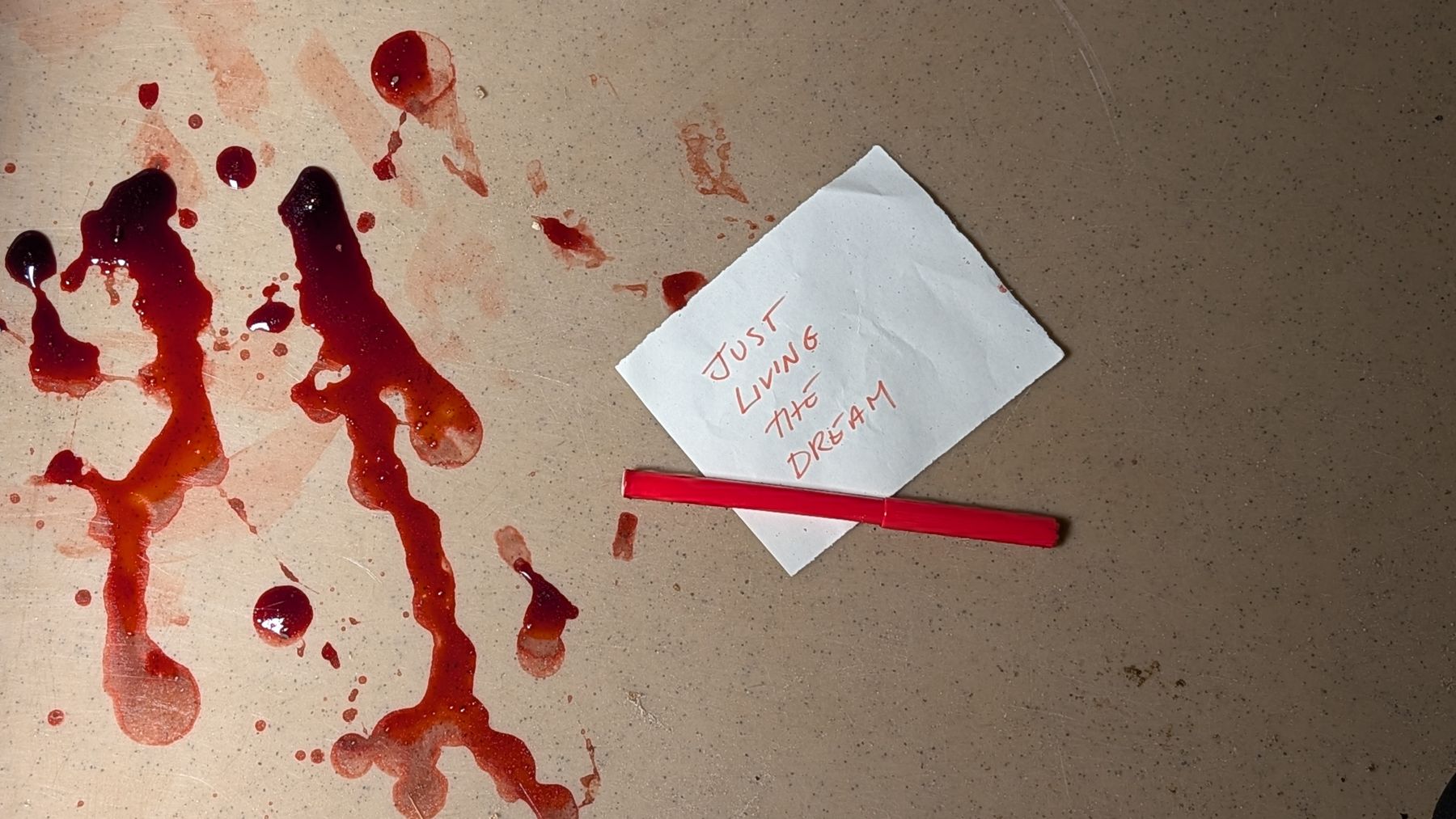 A handwritten note reading Just Living the Dream under a red marker, beside red stains